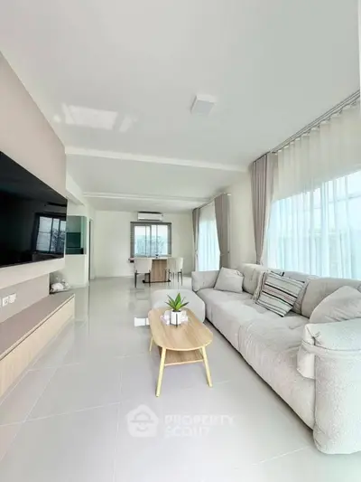 Spacious modern living room with cozy sofa and large TV, perfect for relaxation.