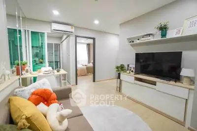 Modern living room with cozy decor and open view to bedroom, featuring stylish furniture and bright lighting.