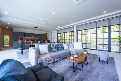 Spacious modern living room with open kitchen and large windows offering natural light.