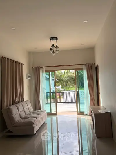 Spacious living room with large sliding doors opening to a balcony with a garden view.