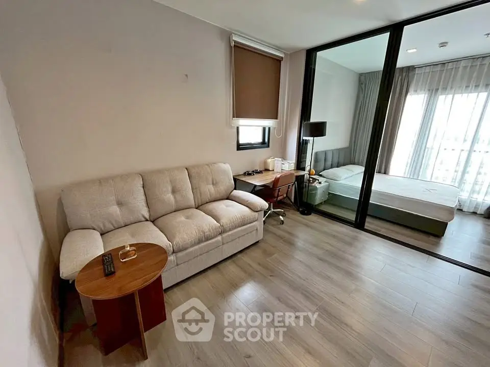 Modern apartment with cozy living room and bedroom separated by glass partition.