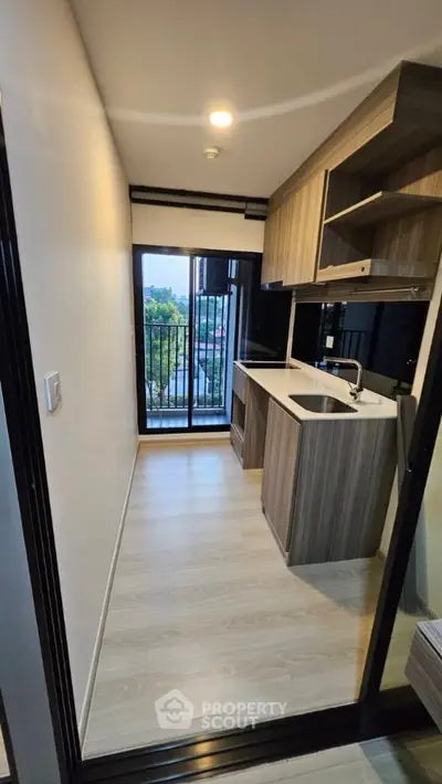 Modern compact kitchen with balcony view in urban apartment
