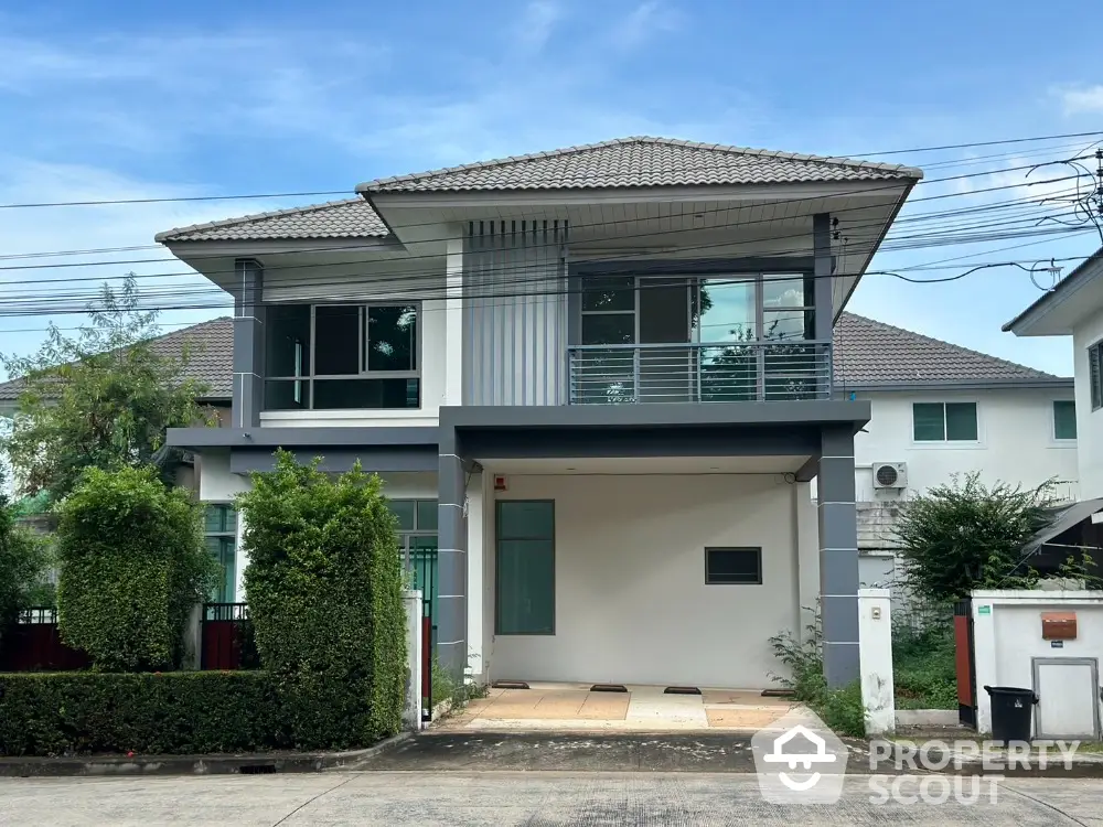 Modern two-story house with sleek design and spacious driveway in suburban neighborhood.