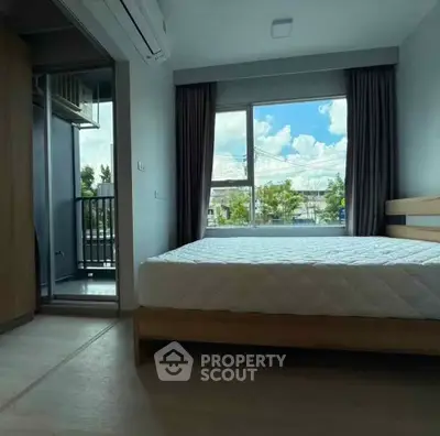 Spacious bedroom with large window and balcony access in modern apartment.