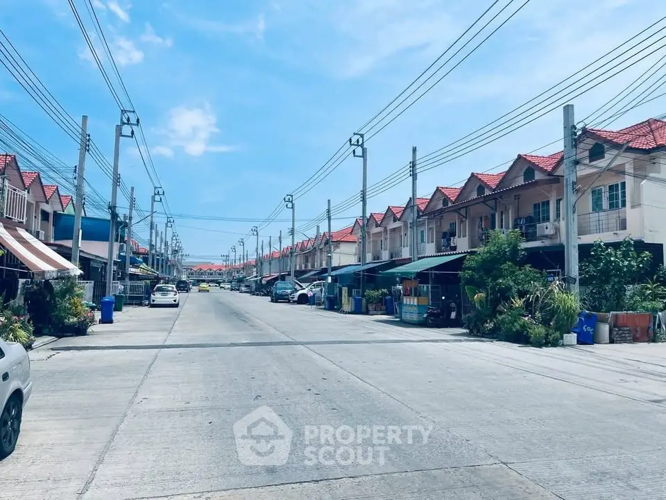 Charming suburban street with rows of townhouses under a clear blue sky, perfect for family living.