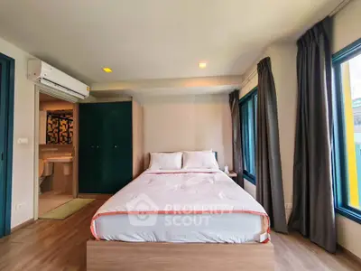Modern bedroom with ensuite bathroom, featuring large windows and stylish decor.