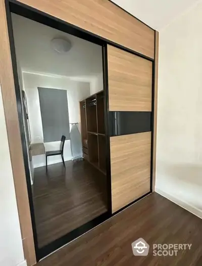 Modern bedroom with sleek mirrored wardrobe and wooden flooring