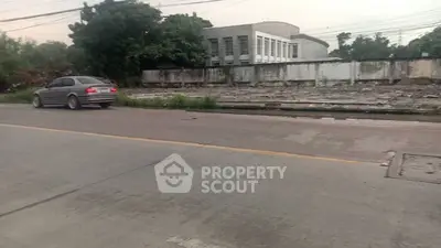 Vacant land plot with potential for development in urban area, featuring paved road access.