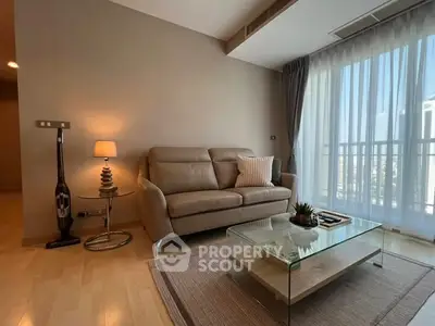 Stylish modern living room with cozy sofa and glass coffee table, featuring floor-to-ceiling windows.