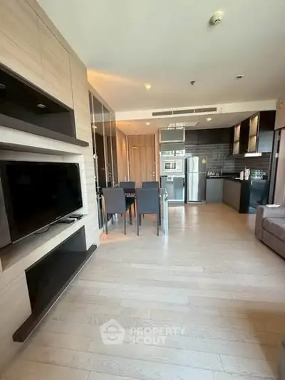 Modern open-plan living room with sleek kitchen and dining area, featuring contemporary design and ample natural light.