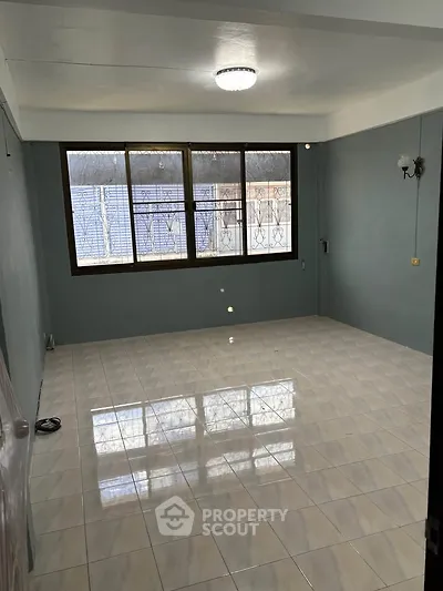 Spacious empty room with large window and tiled floor, perfect for customization.