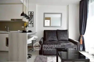 Modern living room with sleek furniture and open kitchen layout, featuring stylish decor and natural light.