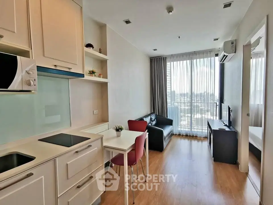 Modern open-layout living room with kitchen, featuring sleek design and large windows for natural light.