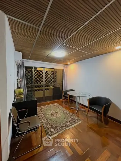 Cozy living room with wooden ceiling and elegant decor, featuring a glass table and stylish chairs.