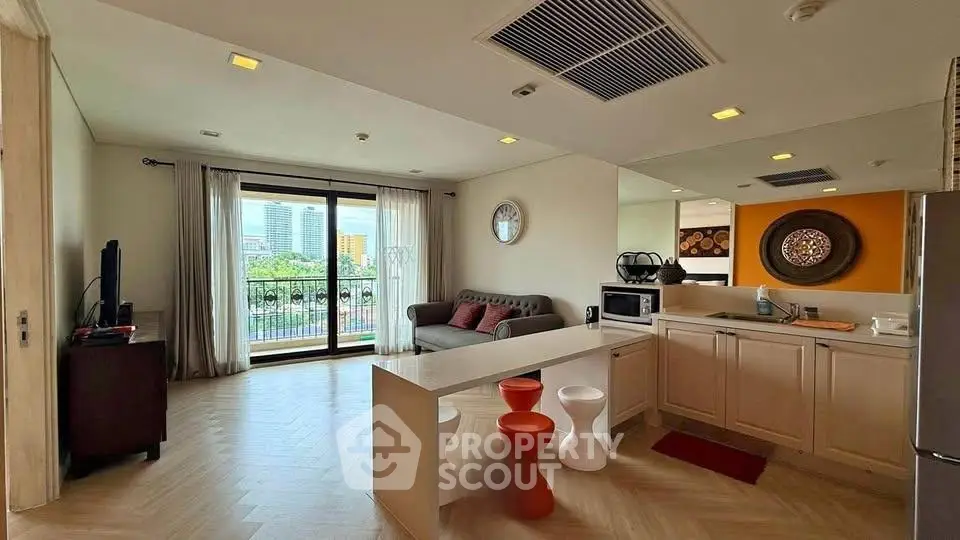 Modern open-layout living room with kitchen, stylish decor, and balcony view in urban apartment.