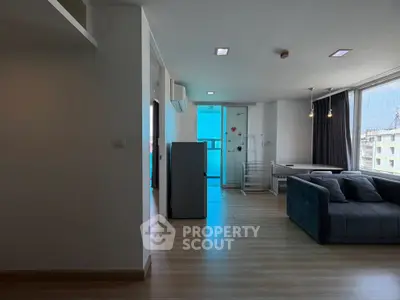 Modern apartment interior with spacious living room and large windows offering city views.