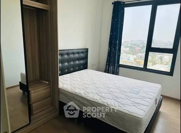 Cozy bedroom with large window offering city view and stylish furnishings.