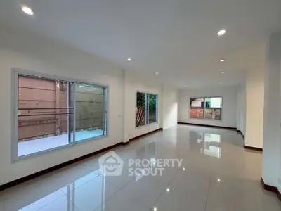 Spacious modern living room with large windows and glossy tiled floors