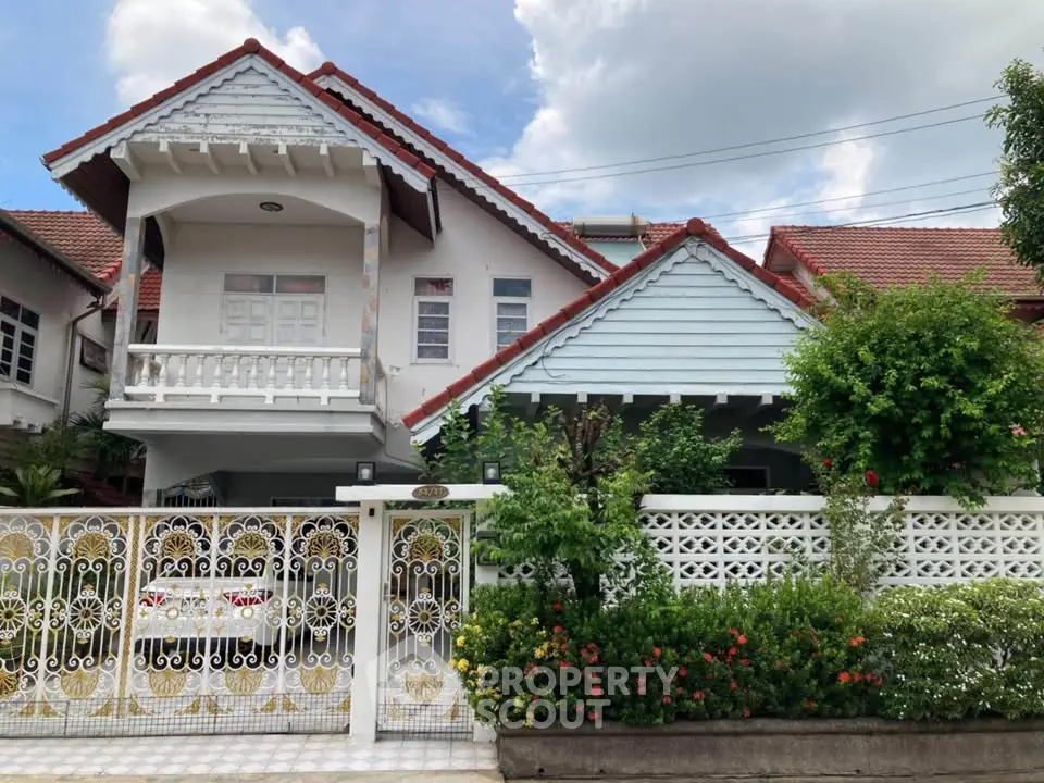 Charming two-story house with red roof and lush garden, perfect for family living.
