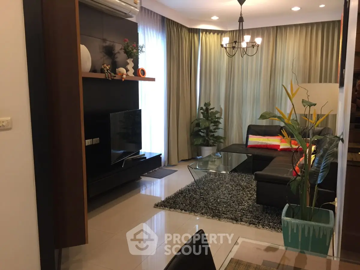 Modern living room with stylish decor, large TV, and cozy seating area in a contemporary apartment.