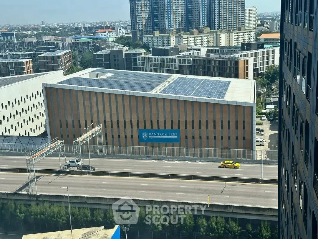 Aerial view of modern urban building with solar panels and cityscape backdrop.