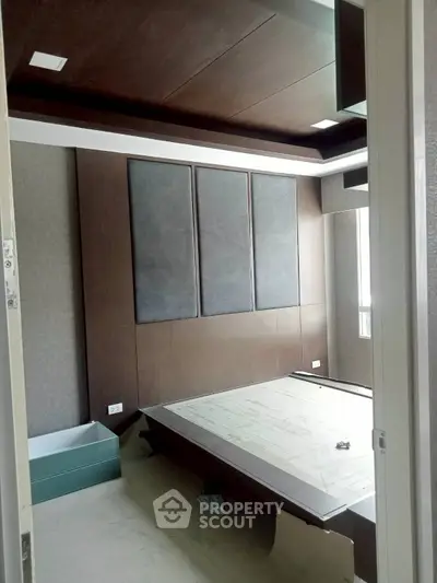 Modern bedroom under construction with sleek paneling and large window.
