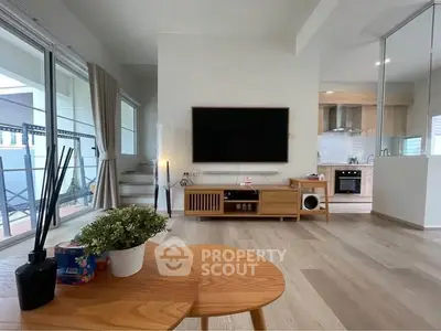 Modern living room with open kitchen, wooden floors, and stylish decor