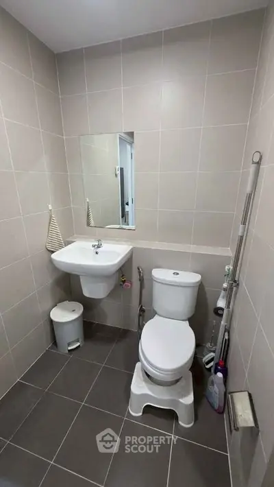 Modern bathroom with sleek fixtures and neutral tiles, featuring a compact design for efficient space use.