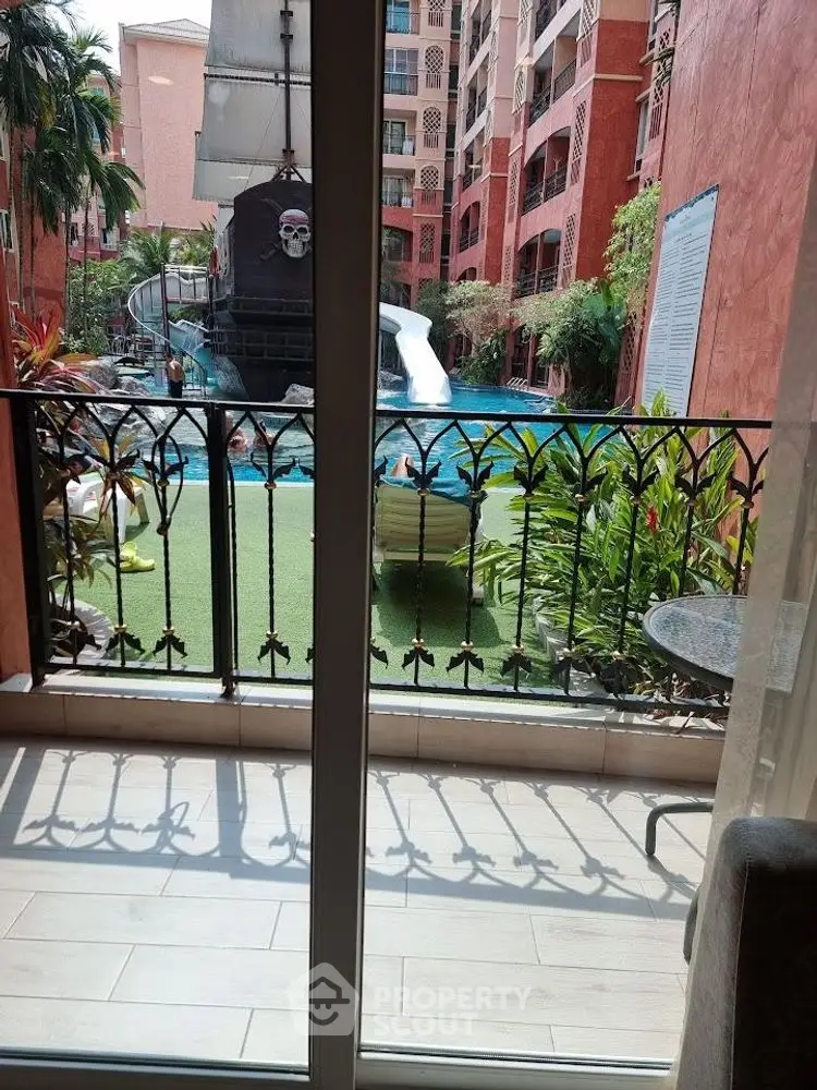 Luxurious pool view from balcony with pirate ship slide in tropical resort.