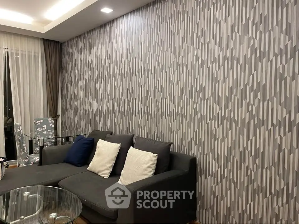 Modern living room with stylish geometric wallpaper and cozy gray sofa