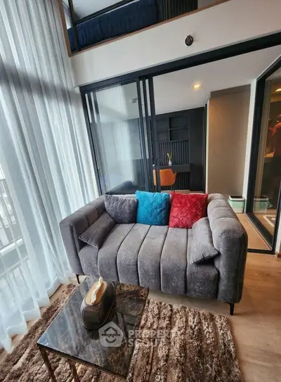 Modern living room with stylish sofa and floor-to-ceiling windows in a contemporary apartment.