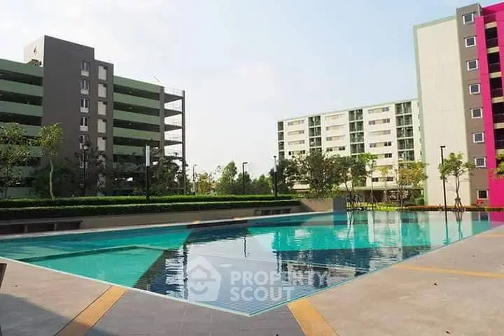 Modern apartment complex with spacious outdoor pool and landscaped surroundings.