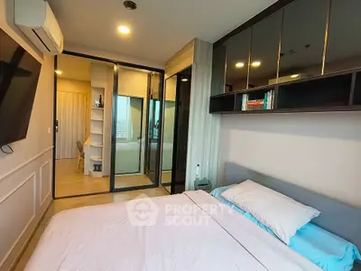 Modern bedroom with sleek design and ensuite bathroom, featuring mirrored wardrobe and wall-mounted TV.