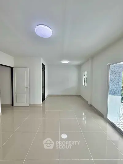 Spacious empty room with glossy tiled floor and large windows
