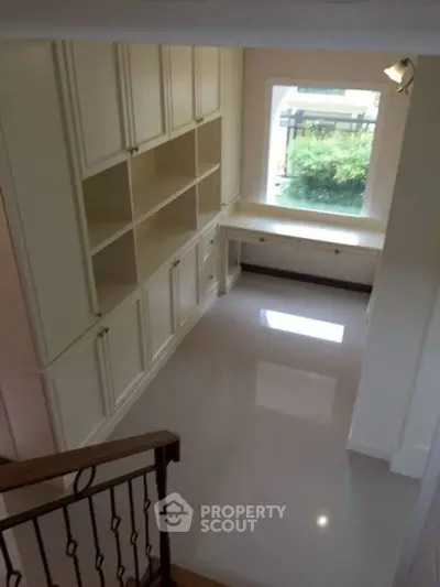 Spacious study room with built-in shelves and large window view