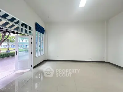 Spacious empty room with large windows and open door to garden view