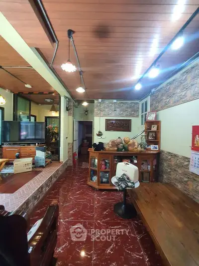 Charming living room with rustic decor and wooden ceiling, featuring cozy seating and elegant lighting.