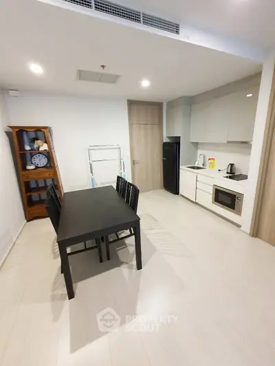 Modern kitchen with dining area, sleek cabinetry, and appliances in a bright, open space.