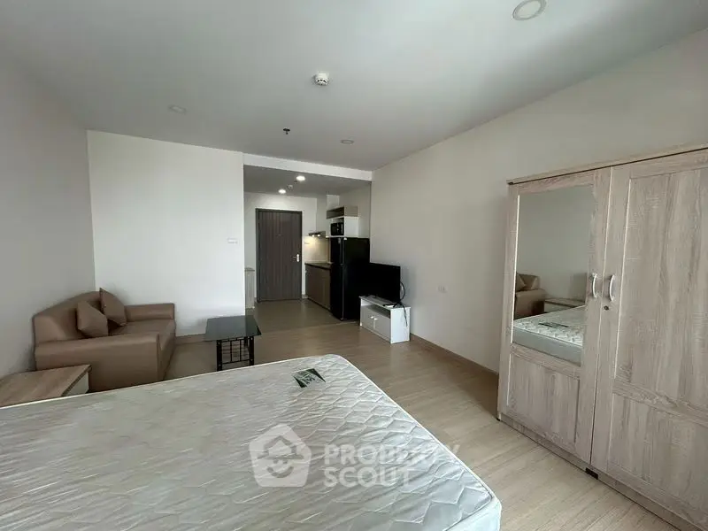 Spacious studio apartment with modern furnishings and open layout, featuring a cozy living area and compact kitchen.
