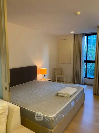 Spacious bedroom with large window and modern furnishings in a stylish apartment.