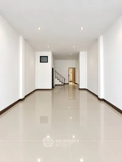 Spacious modern living room with glossy tiled floors and recessed lighting.