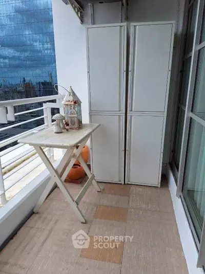 Charming balcony with city view, featuring storage cabinets and a quaint table, perfect for urban living.