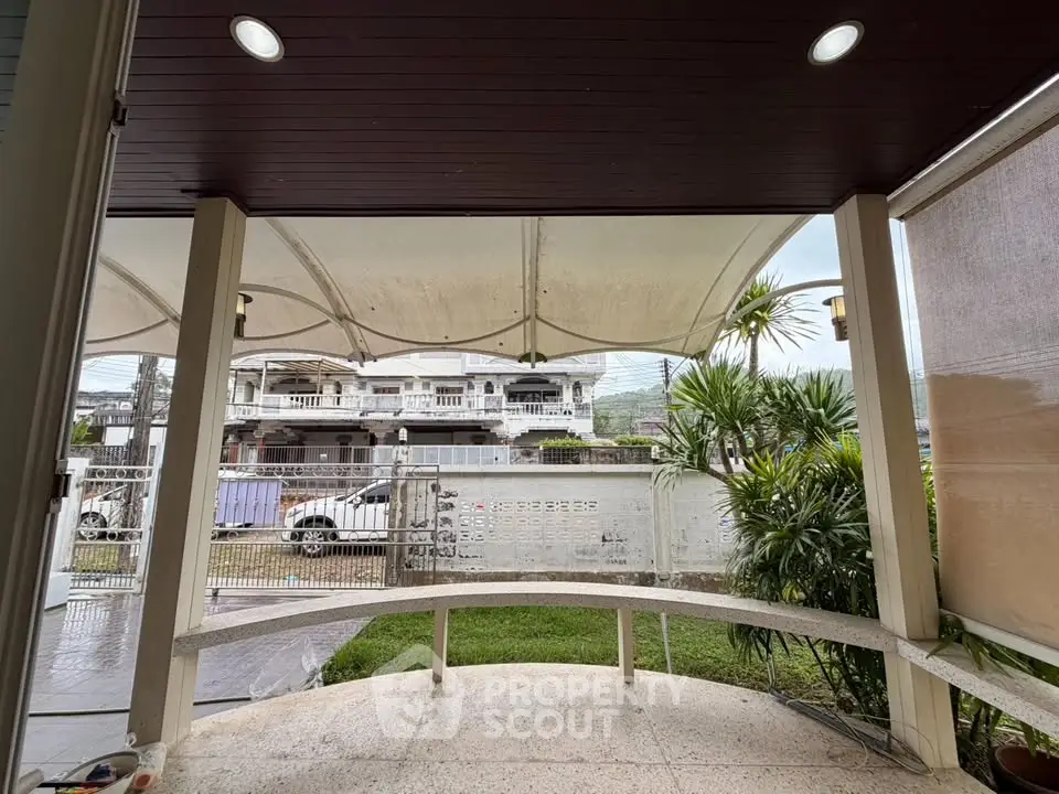 Charming covered patio with garden view and modern lighting, perfect for relaxation.