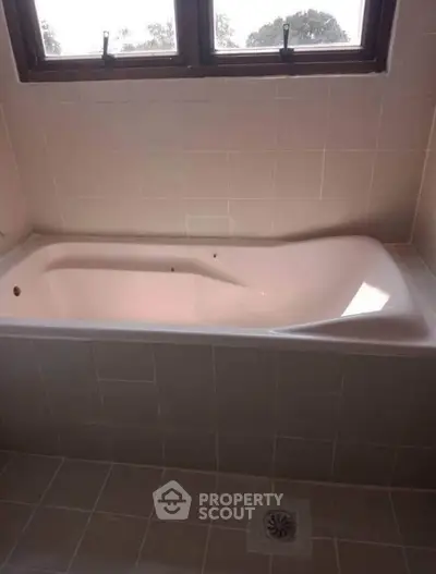 Spacious bathroom with elegant bathtub and natural light from window.