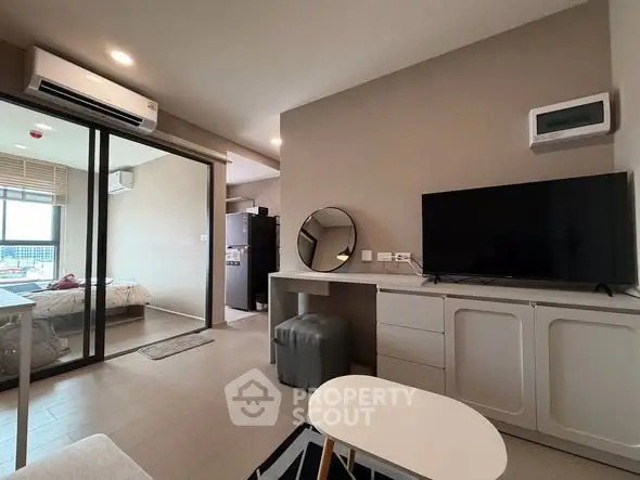 Modern living room with sleek furniture and open layout, featuring a TV and air conditioning.