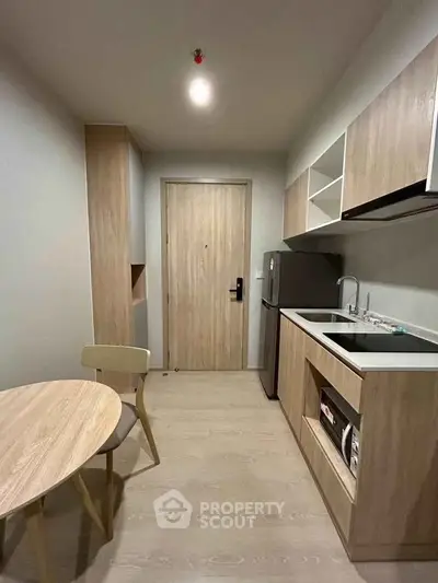 Modern compact kitchen with sleek wooden cabinetry and integrated appliances in a cozy apartment.
