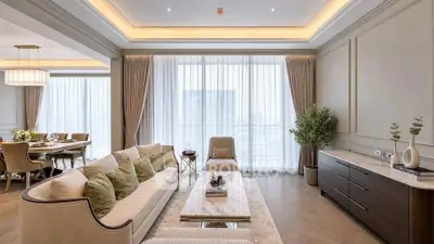 Luxurious living room with elegant decor and dining area, featuring large windows and stylish furnishings.