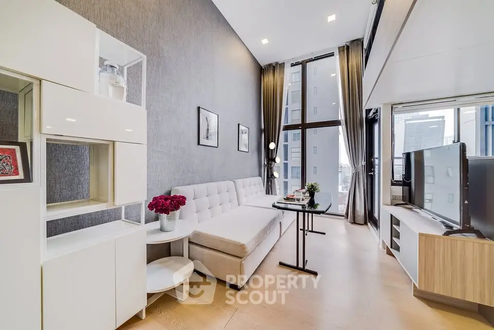Modern living room with high ceilings and large windows offering city views.