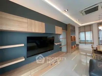 Modern living room with sleek wooden cabinetry and large flat-screen TV