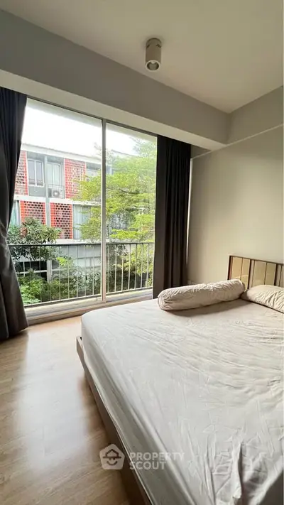 Spacious bedroom with large window and garden view in modern apartment